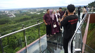 Sejumlah pengunjung berfoto saat berjalan di atas jembatan kaca di glamping Kawasan Inti Pusat Pemerintahan (KIPP) Ibu Kota Nusantara (IKN), Penajam Paser Utara, Kalimantan Timur. Foto: ANTARA FOTO/M Risyal Hidayat