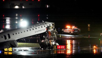Puing-puing menggantung dari sebuah jet Air Canada Express yang rusak setelah bertabrakan dengan truk pemadam kebakaran di Bandara LaGuardia, New York, di Queens, New York, AS, pada 23 Maret 2026 (Adam Gray/Reuters)